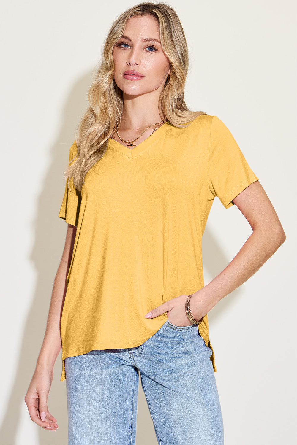 ShopBasicbae bamboo V-neck high-low T-shirt, full size, featuring a relaxed fit and natural fabric, displayed on a hanger.